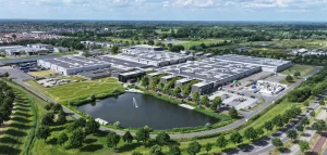 Luchtfoto van modern industrieel complex met zonnepanelen en vijver in groene omgeving