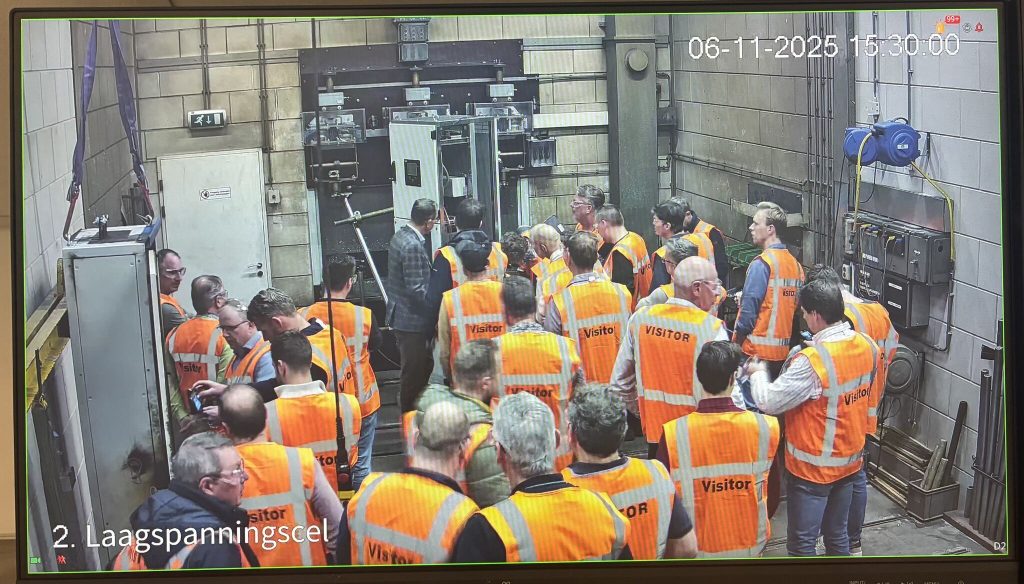 Groep bezoekers in oranje veiligheidsvesten bekijkt industriële machines in fabriek tijdens rondleiding op 6 november 2025