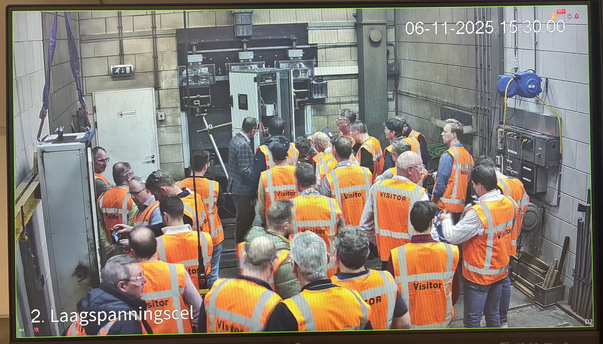 Groep bezoekers in oranje veiligheidsvesten bekijkt industriële machines in fabriek tijdens rondleiding op 6 november 2025