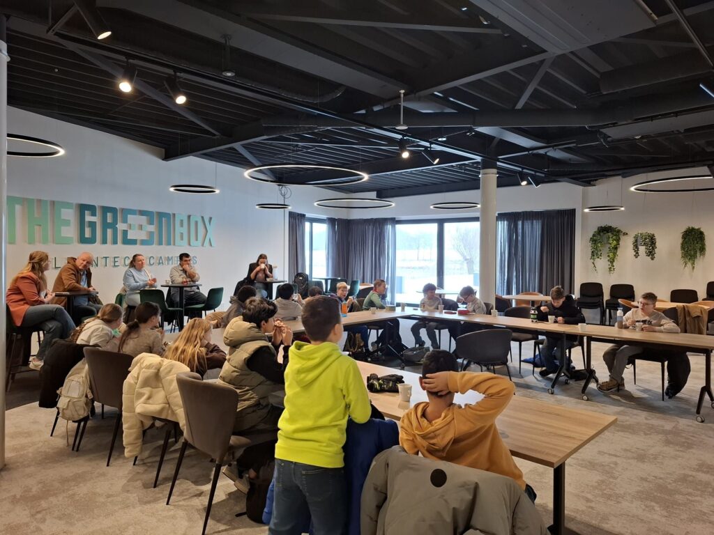 Studenten en professionals in moderne vergaderruimte van The Green Box tijdens een presentatie of workshop sessie.