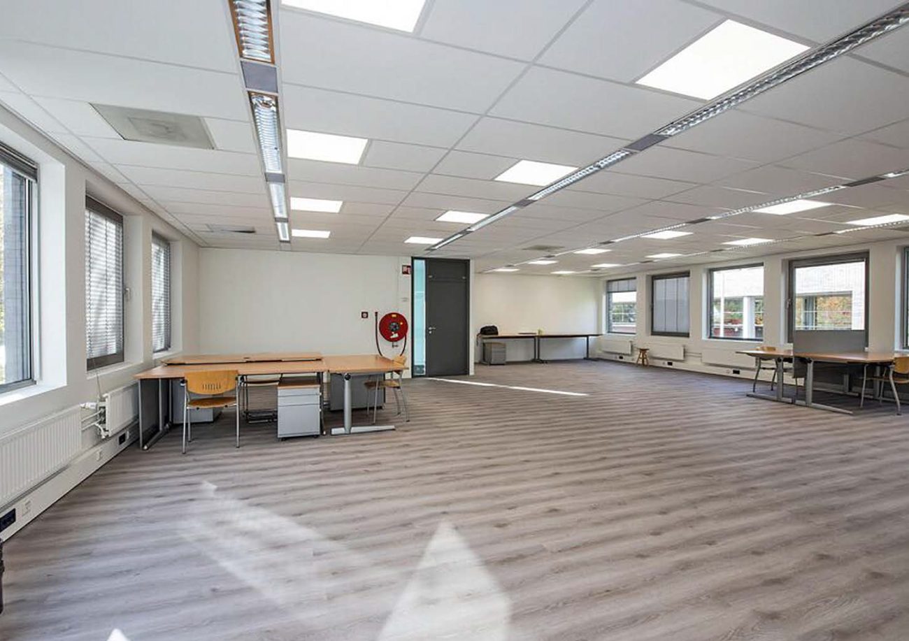 Moderne kantoorruimte met houten vloer, werkplekken langs ramen, plafondverlichting en minimalistische inrichting