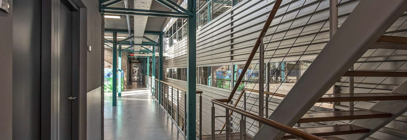 Modern gebouw interieur met metalen trap, groene balken en glazen reling in industriële architectuurstijl