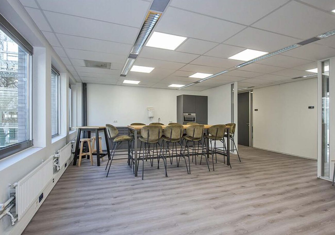 Moderne kantoor breakroom met keukeneiland, barkrukken en grote ramen voor natuurlijk licht